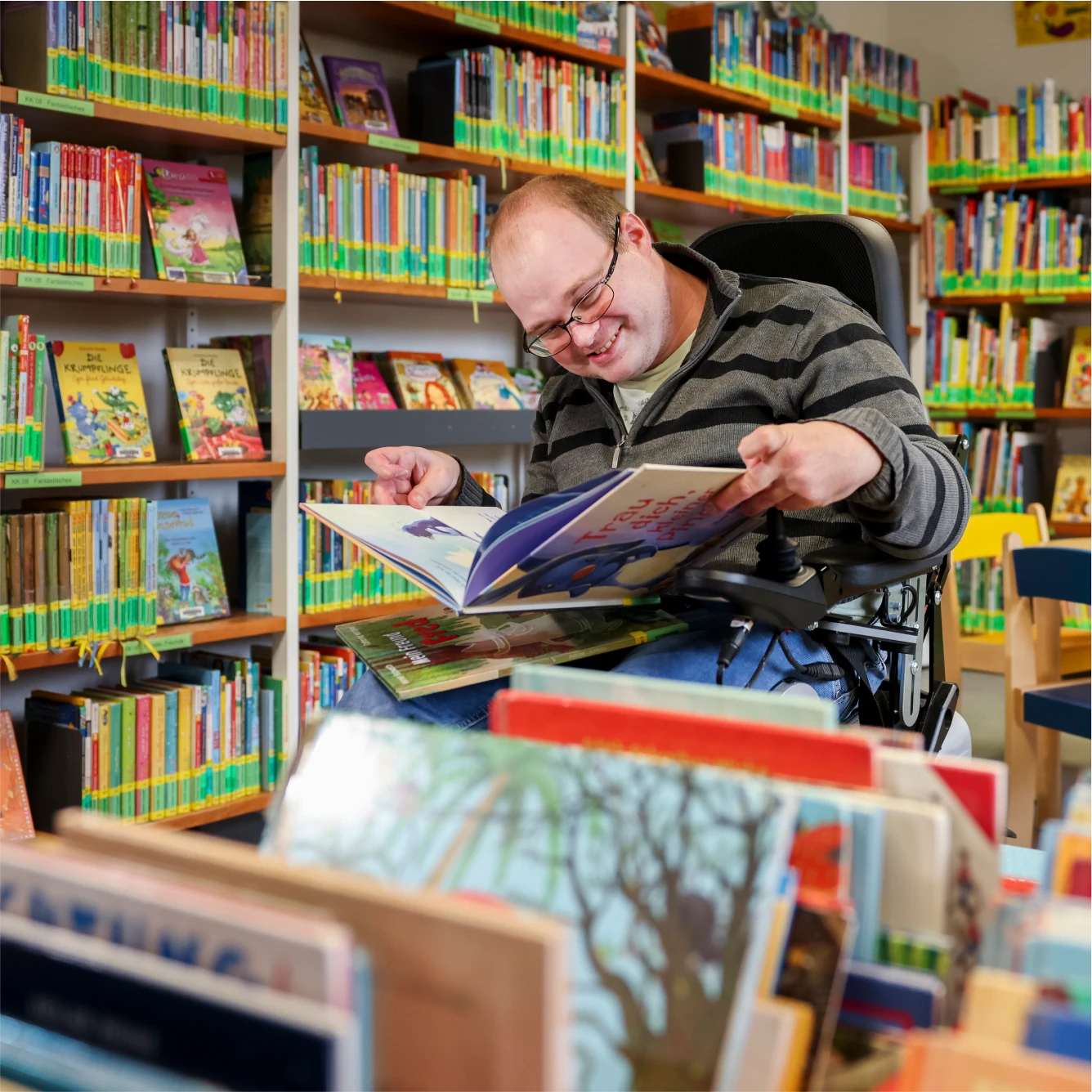 Ein Mann vor einem Bücherregal blättert in einem Buch.